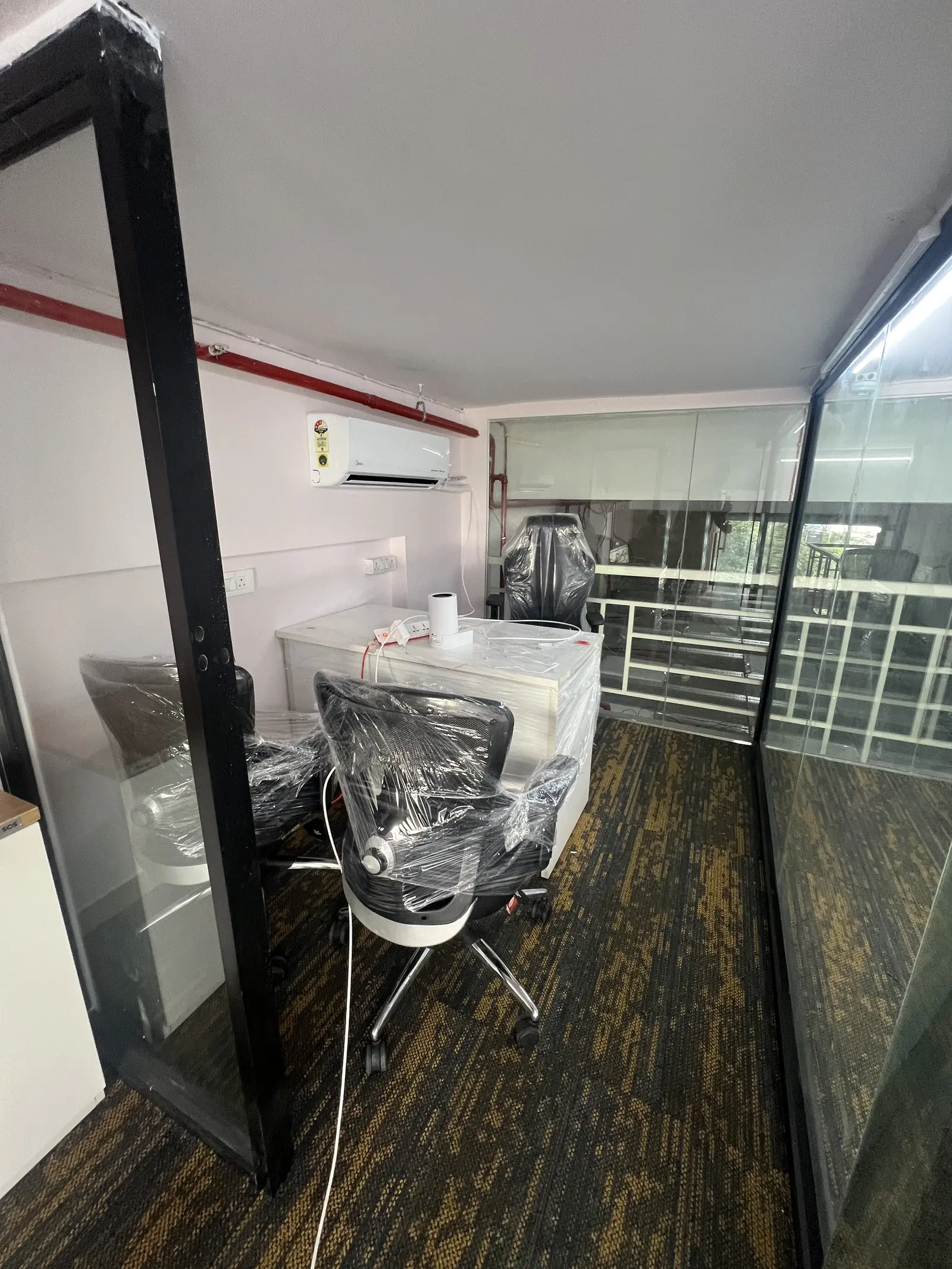 Manager cabin behind black-framed glass, with a desk and two chairs