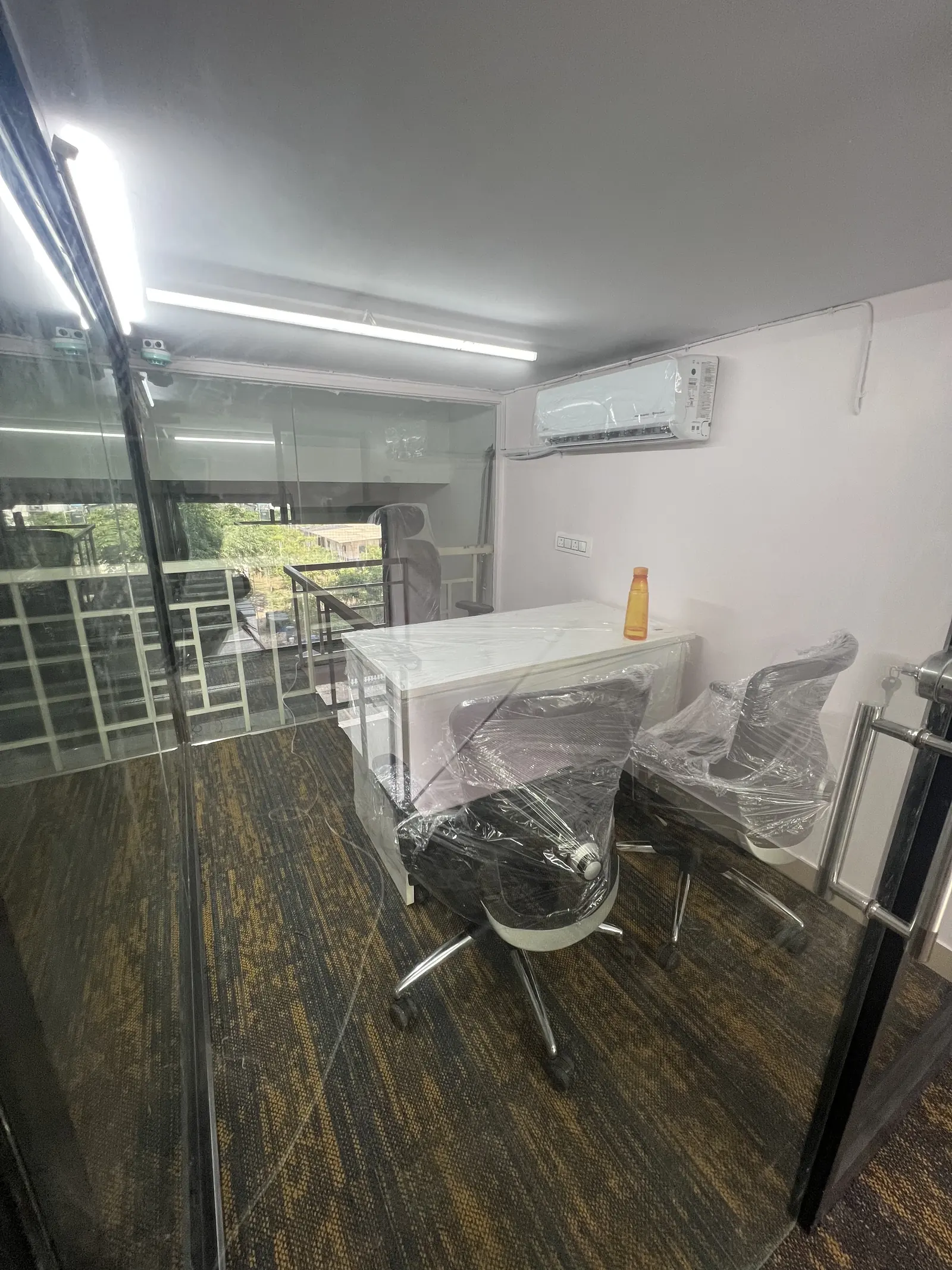 A small office on the upper level, with a desk and two chairs beside a window